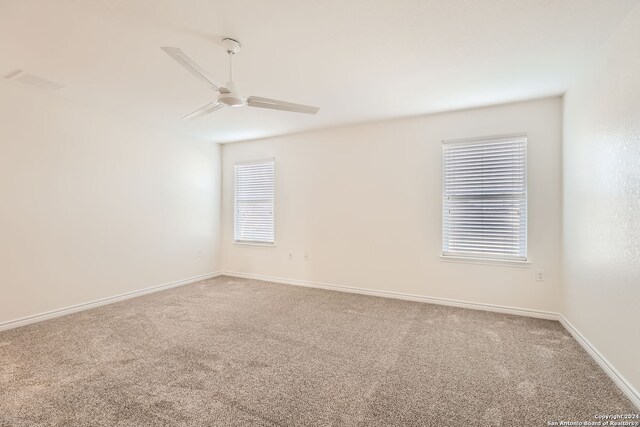 carpeted spare room featuring ceiling fan