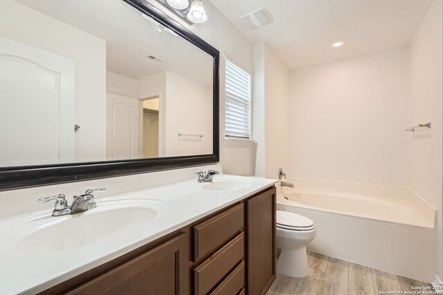 bathroom featuring toilet, a bathtub, vanity, and hardwood / wood-style flooring