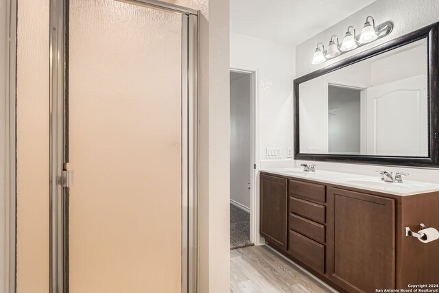 bathroom with wood-type flooring, vanity, and an enclosed shower