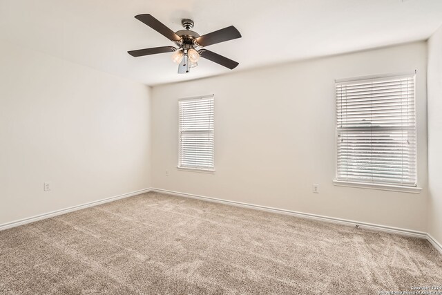 carpeted spare room featuring ceiling fan