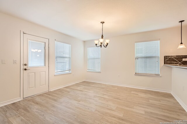 unfurnished dining area with light hardwood / wood-style floors and an inviting chandelier