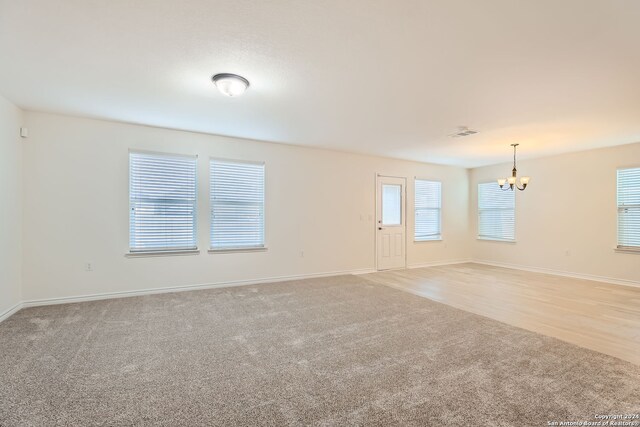 empty room featuring light hardwood / wood-style flooring and an inviting chandelier