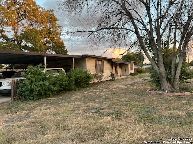 property exterior at dusk with a carport and a lawn