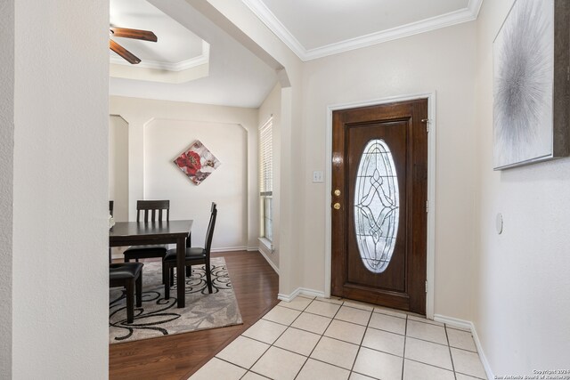 foyer with light wood-type flooring, ceiling fan, and crown molding