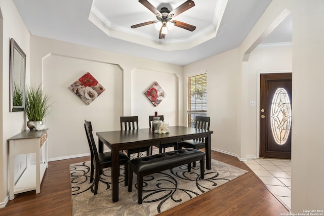 dining space with hardwood / wood-style flooring, ceiling fan, ornamental molding, and a tray ceiling