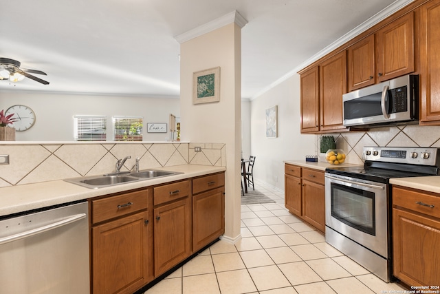 kitchen featuring sink, crown molding, decorative backsplash, light tile patterned floors, and appliances with stainless steel finishes