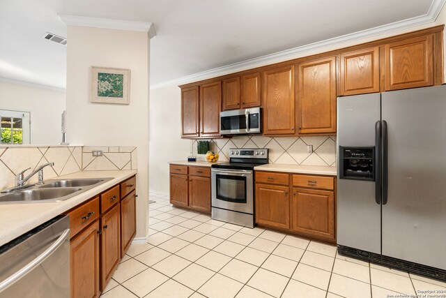 kitchen featuring sink, crown molding, decorative backsplash, light tile patterned flooring, and appliances with stainless steel finishes