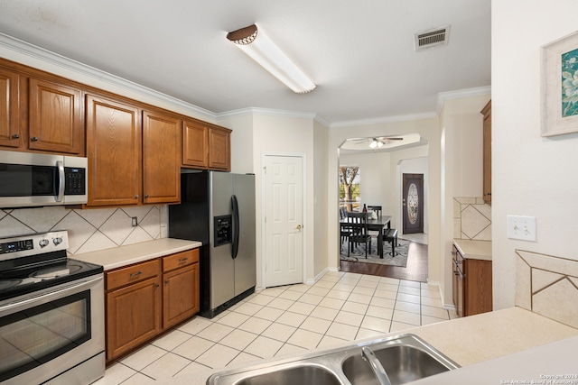 kitchen featuring backsplash, ceiling fan, ornamental molding, and appliances with stainless steel finishes