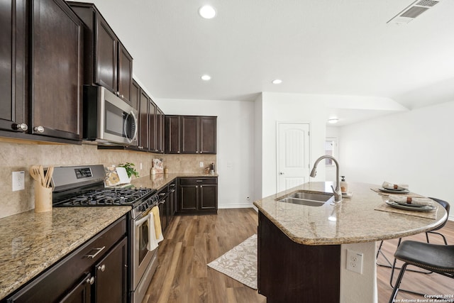 kitchen featuring sink, a kitchen breakfast bar, wood-type flooring, a center island with sink, and appliances with stainless steel finishes