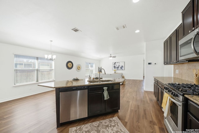 kitchen with sink, dark wood-type flooring, decorative light fixtures, and appliances with stainless steel finishes