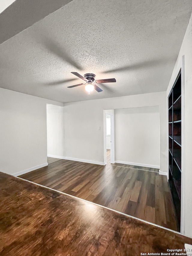 unfurnished room with a textured ceiling, dark hardwood / wood-style floors, and ceiling fan