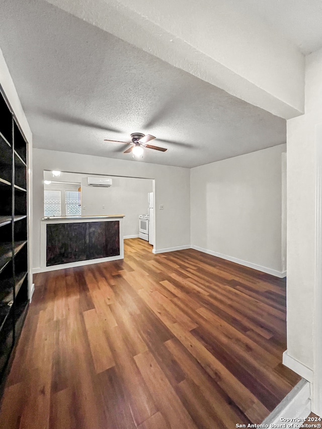 unfurnished living room featuring ceiling fan, wood-type flooring, a textured ceiling, and a wall unit AC