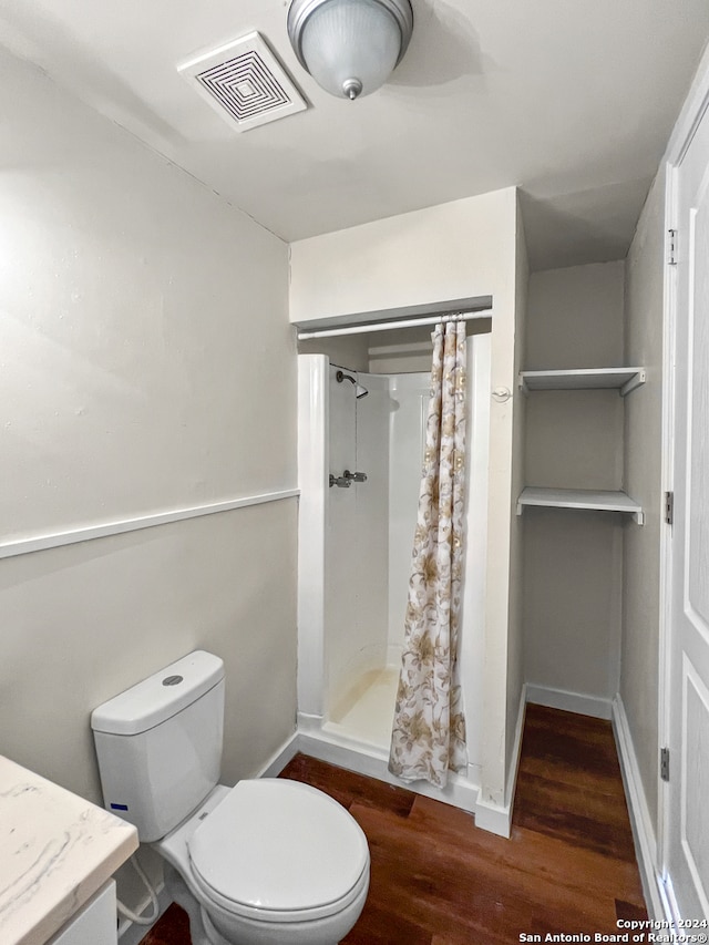 bathroom with hardwood / wood-style flooring, vanity, curtained shower, and toilet