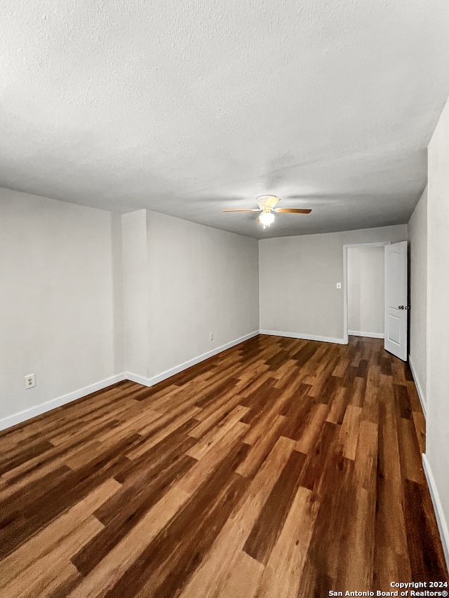 spare room featuring a textured ceiling, ceiling fan, and dark wood-type flooring