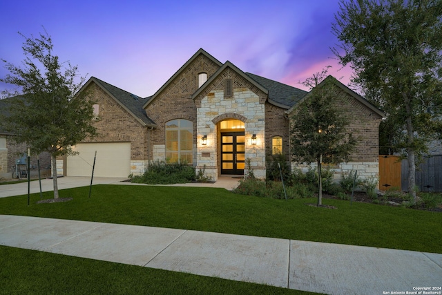 french country inspired facade with a lawn, a garage, and french doors