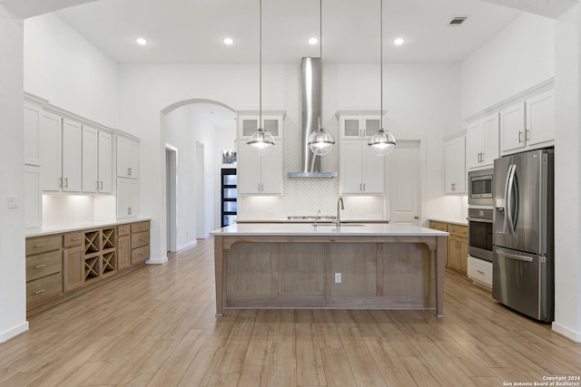 kitchen with a large island, white cabinets, light wood-type flooring, and appliances with stainless steel finishes