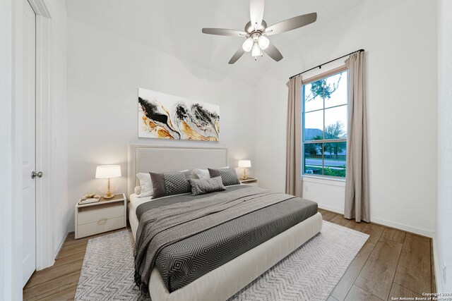 bedroom featuring ceiling fan, light hardwood / wood-style floors, and vaulted ceiling