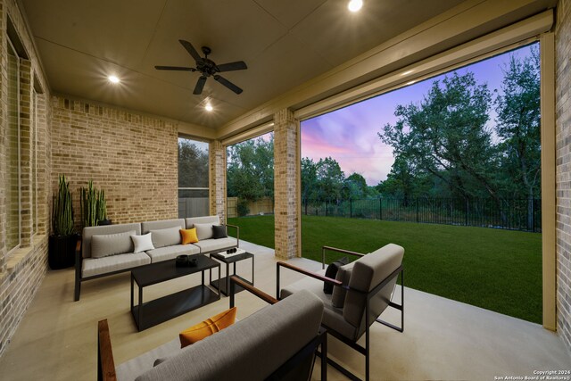 patio terrace at dusk featuring a lawn, ceiling fan, and an outdoor hangout area