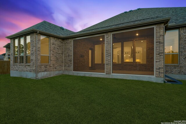 back house at dusk with a lawn