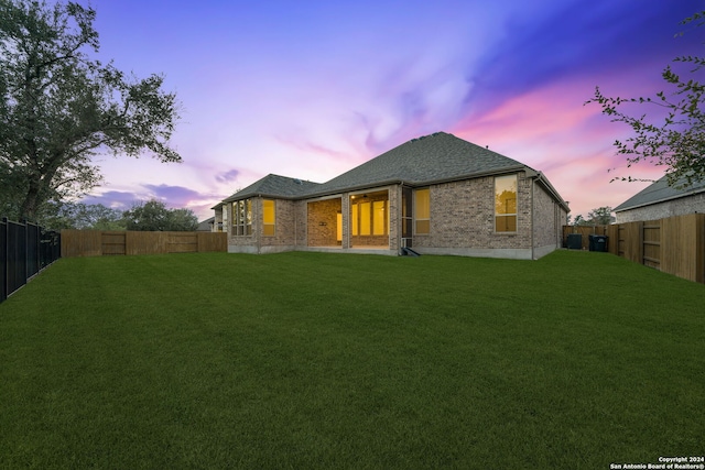 back house at dusk featuring a yard