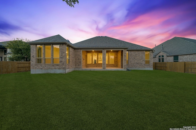 back house at dusk featuring a yard