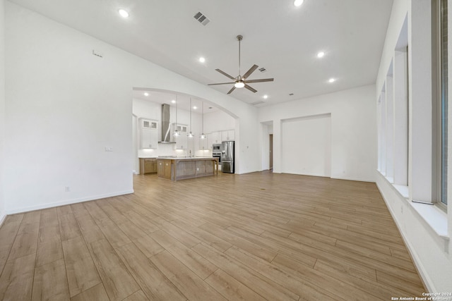 unfurnished living room featuring ceiling fan and light hardwood / wood-style floors