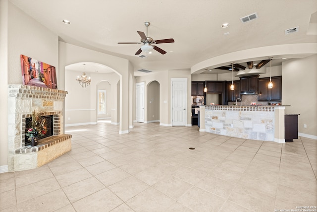 tiled living room featuring ceiling fan with notable chandelier and sink