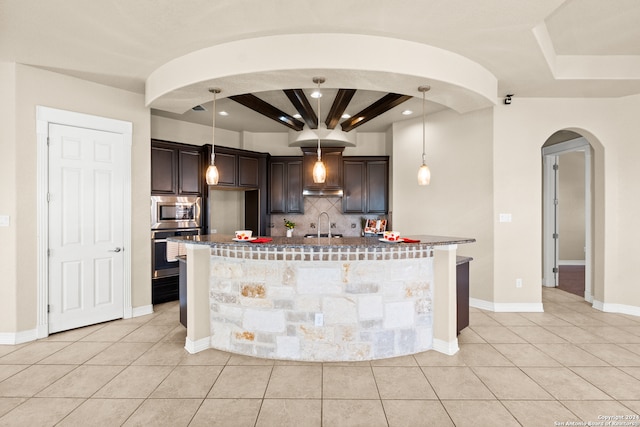 kitchen with backsplash, hanging light fixtures, light tile patterned floors, dark brown cabinets, and stainless steel appliances