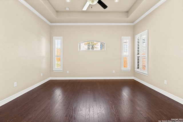 spare room featuring ceiling fan, ornamental molding, dark wood-type flooring, and a tray ceiling