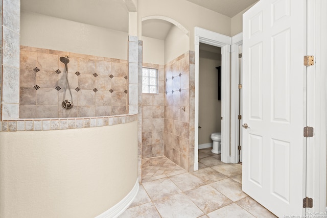 bathroom with tiled shower and toilet