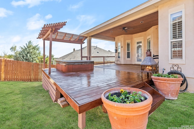 wooden terrace with a pergola, ceiling fan, a lawn, and a hot tub