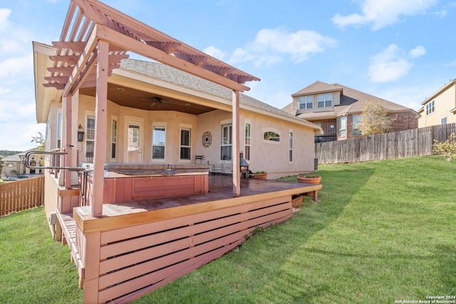 rear view of house featuring a pergola, a wooden deck, a yard, and a hot tub