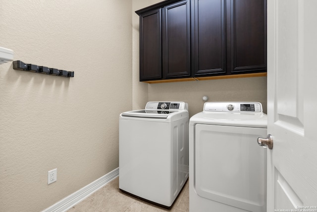 laundry area featuring washer and dryer, light tile patterned flooring, and cabinets