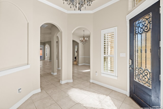 foyer entrance with a notable chandelier, light tile patterned floors, and crown molding