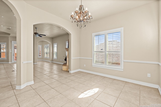 spare room featuring a textured ceiling, ceiling fan with notable chandelier, and light tile patterned flooring