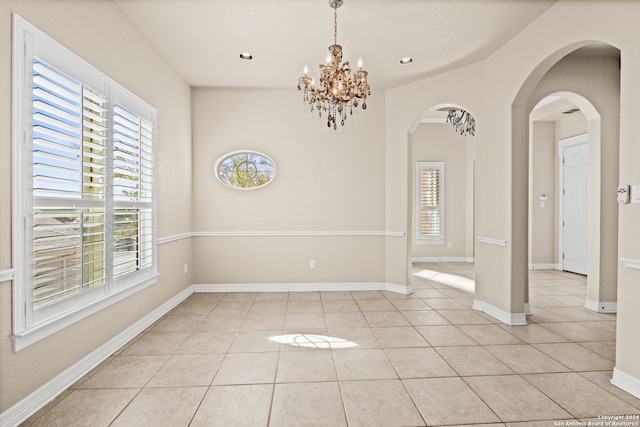 tiled empty room with an inviting chandelier