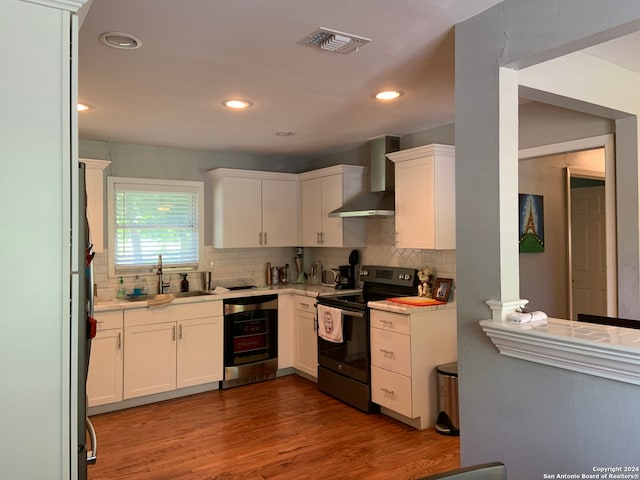 kitchen featuring white cabinetry, sink, wall chimney exhaust hood, black electric range, and light hardwood / wood-style floors