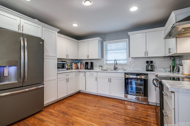 kitchen with white cabinetry, sink, stainless steel appliances, wine cooler, and light hardwood / wood-style floors