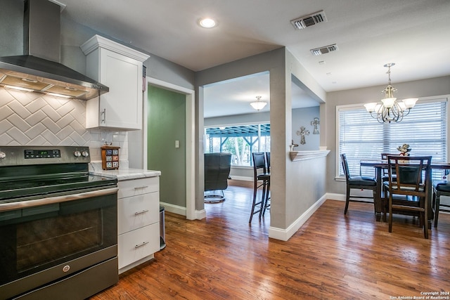 6531 Fox Run, San Antonio, TX 78233 - kitchen with stainless steel electric range, wall chimney range hood, a chandelier, white cabinetry, and decorative backsplash