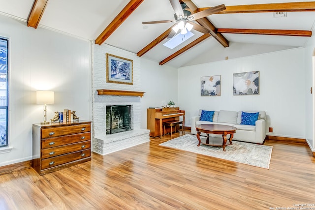 living room with vaulted ceiling with skylight, light hardwood / wood-style floors, and a brick fireplace