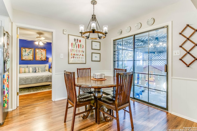 dining room featuring ceiling fan with notable chandelier and light hardwood / wood-style floors