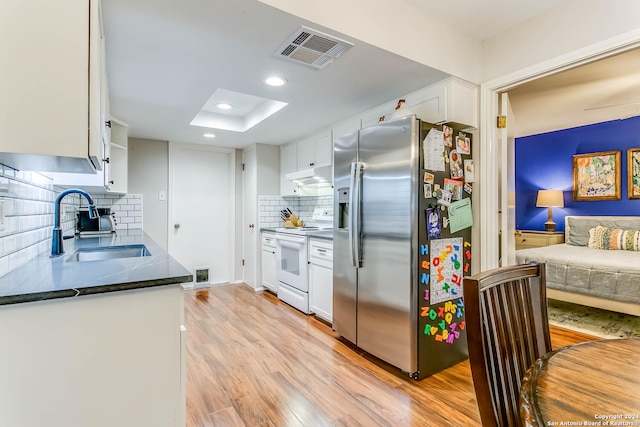 kitchen with backsplash, white cabinets, stainless steel fridge, white electric range oven, and light hardwood / wood-style floors