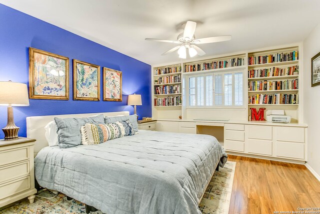 bedroom with ceiling fan, built in desk, and light hardwood / wood-style floors