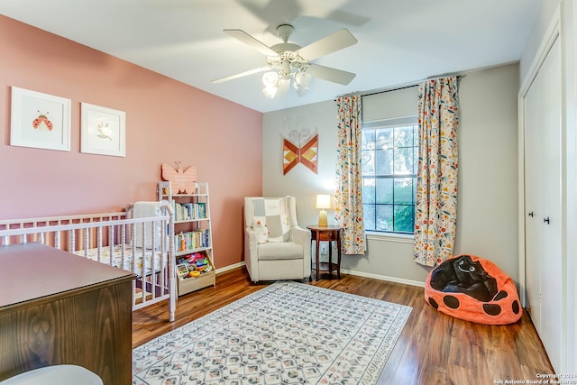 bedroom with a closet, hardwood / wood-style flooring, a nursery area, and ceiling fan