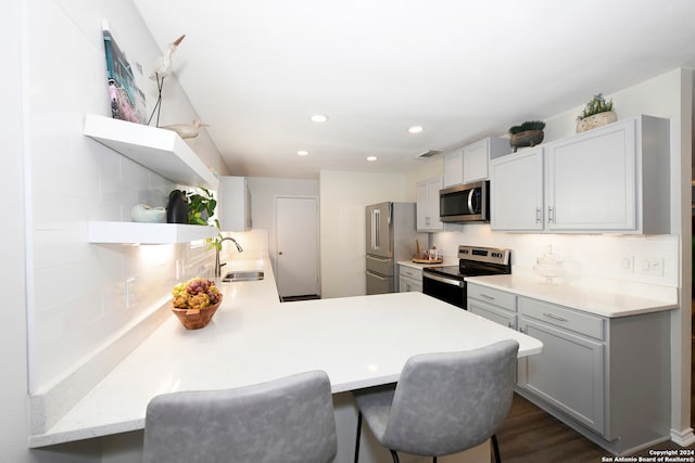 kitchen featuring backsplash, a kitchen breakfast bar, sink, appliances with stainless steel finishes, and kitchen peninsula