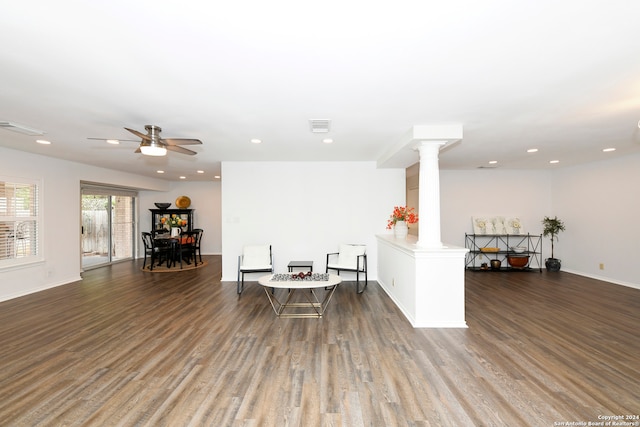 living area with dark hardwood / wood-style floors, ceiling fan, and decorative columns