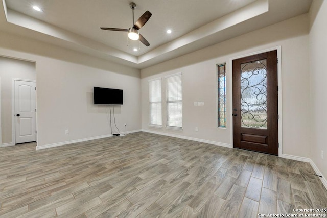 foyer entrance featuring a tray ceiling, ceiling fan, and light hardwood / wood-style floors