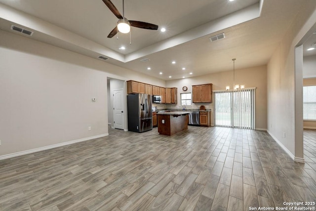 kitchen with sink, a center island, pendant lighting, ceiling fan with notable chandelier, and appliances with stainless steel finishes