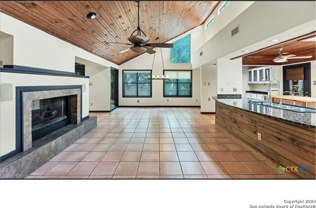 unfurnished living room with a premium fireplace, sink, light tile patterned flooring, and wood ceiling