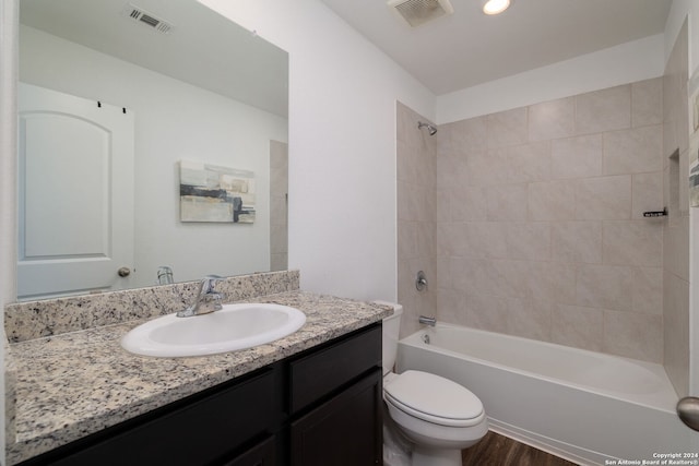 full bathroom with vanity, hardwood / wood-style flooring, toilet, and tiled shower / bath